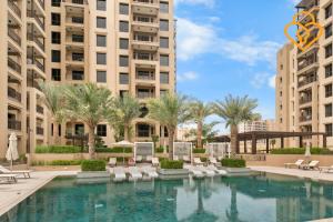 - une piscine bordée de palmiers et de bâtiments dans l'établissement Keysplease 1 BR Apt, Madinat Jumeirah Living, à Dubaï