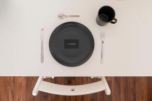 a white table with a black plate and utensils at Harmony Stay Center Xanthi - Meno Homes 6A in Xanthi