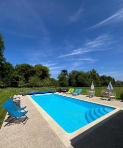uma piscina com espreguiçadeiras azuis em Chambres d'hôtes Château de La Croix Chemin em Saint-Léger-des-Prés