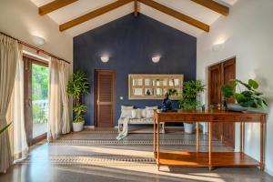a living room with a table and a blue wall at SaffronStays Sweet Mango - 4BR Goan Villa w Private Pool, Mango Garden, Bar Gazebo & Vibrant Interiors Near Beaches in Parra