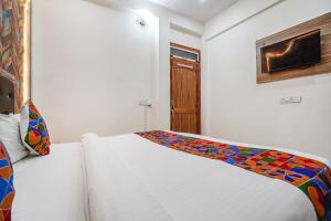 ein Schlafzimmer mit einem weißen Bett und einer bunten Decke darauf in der Unterkunft FabHotel Siya Bihari in Ayodhya