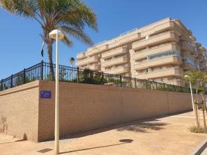 ein Gebäude mit einer Mauer und einer Palme und einer Straßenlaterne in der Unterkunft Playa Ribera MED007 in La Estación