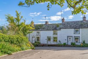 an exterior view of a white house with a driveway at L'al Cottage, Sockbridge in Penrith