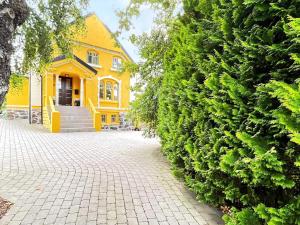a yellow house with a large green hedge at 10 person holiday home in arendal-By Traum in Arendal +6 photos
