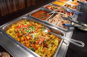 ein Buffet mit vielen verschiedenen Speisen in Tabletts in der Unterkunft Faran Hotel in Karatschi