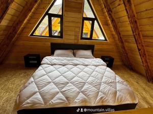 een groot bed in een kamer met 2 ramen bij The Mountain Villas in Hankavan