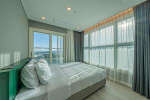 a bedroom with a bed and a large window at Chestertons Naksan in Yangyang