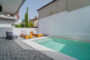 a swimming pool with two lounge chairs next to a house at Poseidon close to the beach in Agios Nikolaos