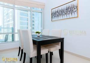 Ultima Vacation Homes loft 1 BR Apartment في دبي: غرفة طعام مع طاولة سوداء وكراسي بيضاء
