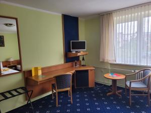 Habitación con escritorio, ordenador y 2 sillas. en City-Hotel Cottbus en Cottbus