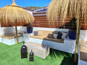 a patio with a couch and umbrella and grass at Casa Pozuelo in Taramay