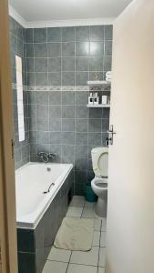 a bathroom with a bath tub and a toilet at Shiloh Inn in Gaborone