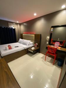 a bedroom with a bed and a desk and a red chair at Hotel Sogo - EDSA Trinoma in Manila