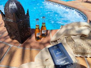 two bottles of beer sitting next to a swimming pool at Casa Pozuelo in Taramay