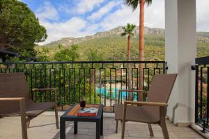 einen Balkon mit Stühlen und einem Tisch sowie Poolblick in der Unterkunft Morina Deluxe Hotel in Oludeniz