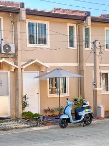 a scooter parked in front of a house with an umbrella at Palawan Homestay in Puerto Princesa City