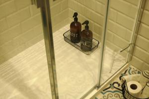 2 bottiglie di alcol sono sedute su un box doccia di Magione 10 a Siena