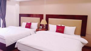 薩帕的住宿－自由沙巴酒店，配有白色和红色枕头的酒店客房内的两张床