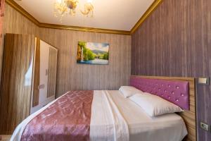 een slaapkamer met een groot bed met een paars hoofdeinde bij Royal Babil Suites Hotel in Trabzon