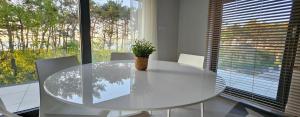 a white dining room table with a potted plant on it at Pine & Sun Apartment - Hevenia Pogorzelica in Pogorzelica