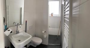 a white bathroom with a sink and a toilet at Bed and Breakfast Oomes Huus in Den Hoorn