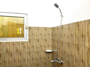 La salle de bains est pourvue d'une douche et d'un mur en bois. dans l'établissement Appartement Terracotta, à Godomè