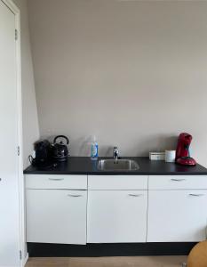a kitchen with white cabinets and a sink at Bed and Breakfast Oomes Huus in Den Hoorn