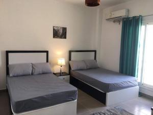 two beds sitting in a room with a window at شاليه للايجار بقريه أمواج in El Alamein