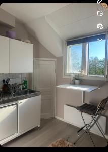 une cuisine avec des armoires blanches, un évier et une fenêtre dans l'établissement Yksiö lähellä Kupittaa Rautatieasemaa Turku, à Turku