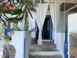 a porch with white curtains and a plant at La Casetta di Valeria - sea and port view in Malfa +15 photos
