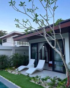 dos sillas blancas sentadas frente a una casa en Villa Anela en Puerto Princesa
