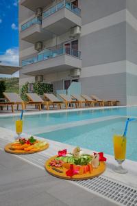 dos platos de comida y bebida junto a una piscina en Heksamil Hotel en Ksamil