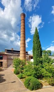 Natura في Masseboeuf: مدخنة طوب طويلة بجانب مبنى به شجرة