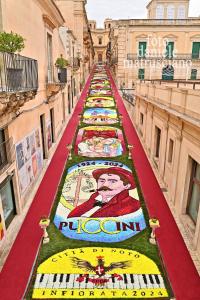 a long road with mosaics on the sides of buildings at Donna Maddalena in Noto