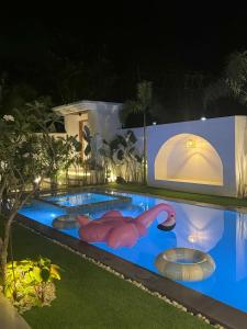 una piscina por la noche con flamencos en el agua en Villa Anela, en Puerto Princesa City