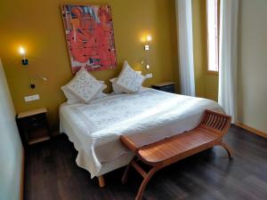 a bedroom with a large bed with a wooden bench at Les Arcades Le Lion D'or in Buis-les-Baronnies +53 photos
