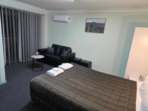 ein Hotelzimmer mit einem Bett und einem Sofa in der Unterkunft Lake Forbes Motel in Forbes