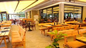 un restaurant avec des tables en bois, des bancs et des fenêtres dans l'établissement Villa Emma, à Nago-Torbole