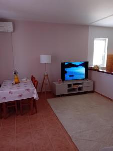Apartmani Lucia في راب: غرفة معيشة مع تلفزيون وطاولة