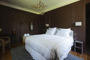 Un dormitorio con una gran cama blanca y una lámpara de araña. en Maison de Magescq, en Magescq