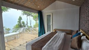 a bedroom with a bed and a balcony at Instaview Kanatal in Tehri-Garhwāl