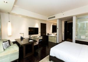 The EL DE Belwood Hotel By Delhi Airport في نيودلهي: غرفة فندقية فيها سرير ومكتب وتلفزيون