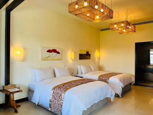 2 camas en una habitación de hotel con lámparas de araña en Kenting Summerland Garden Resort, en Eluan