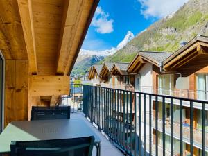 uma varanda com mesa, cadeiras e montanhas em Peaky Riders Self Check-in Hotel em Zermatt