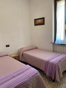 2 bedden in een kamer met paarse lakens bij La casina nel Borgo in Cetona