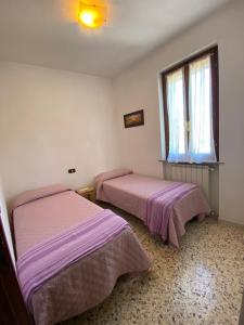 two beds in a room with pink sheets at La casina nel Borgo in Cetona