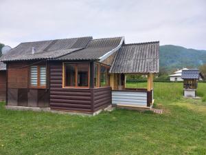 ein kleines Holzhaus auf einem Grasfeld in der Unterkunft Садиба Федорчуків За рікою1 in Scheschory