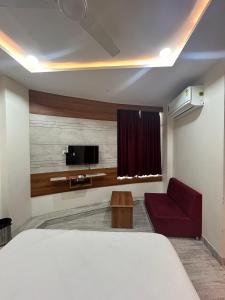 a room with a bed and a tv and a couch at Hotel Hill View in Gandhinagar