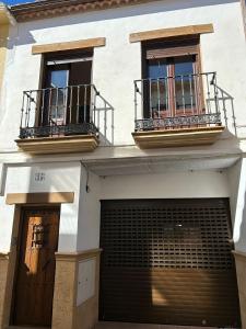 un bâtiment blanc avec deux portes de garage et deux balcons dans l'établissement La Huella del Cuero, à Siles