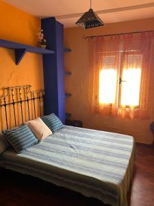 une chambre avec un lit avec des draps bleus et une fenêtre dans l'établissement La Huella del Cuero, à Siles